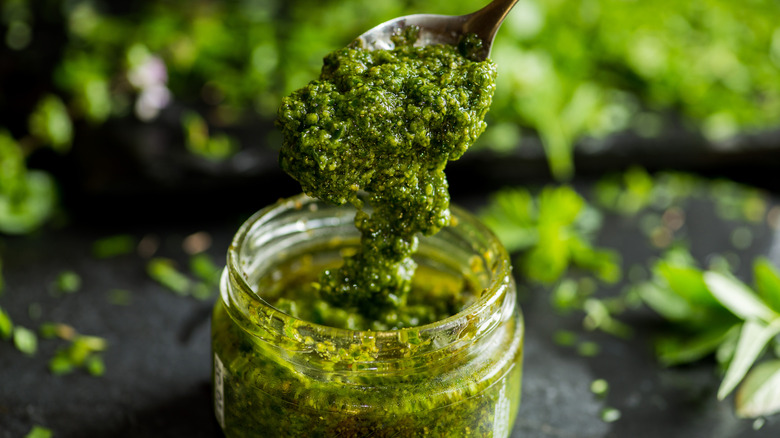 Pesto sauce spooned out of a jar.