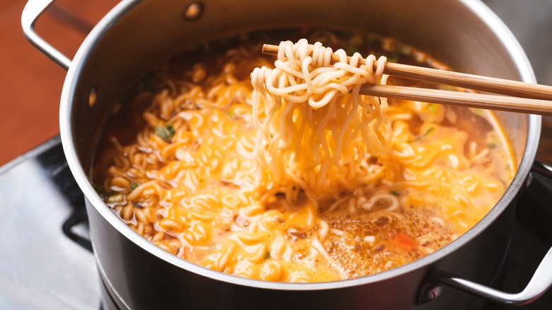 Pot of ramen and chopsticks pulling up noodles
