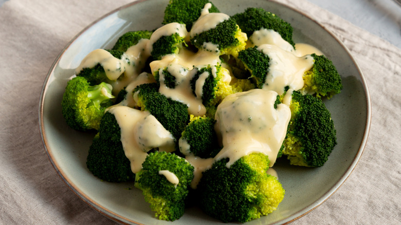 Cheese sauce atop a plate of broccoli florets.