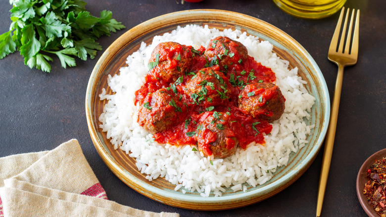 Meatballs and red sauce on a bed of white rice.