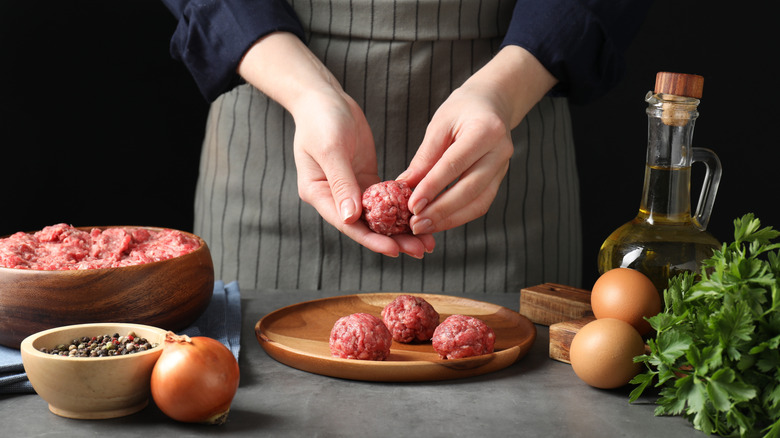 Cook making a batch of meatballs.