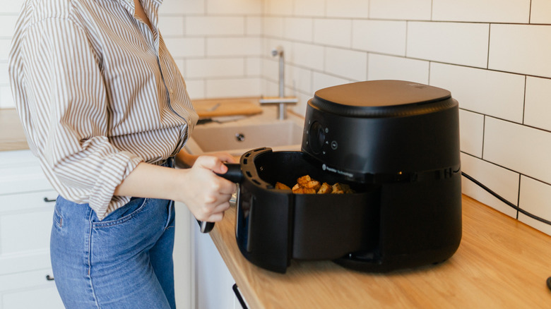 A person making crispy potatoes in an air fryer