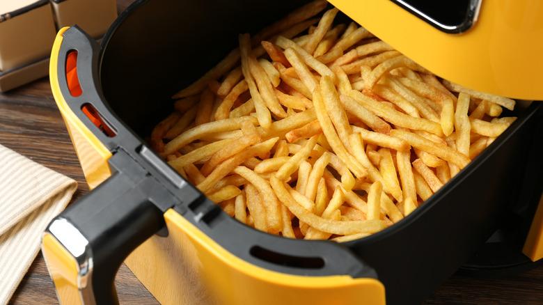 Air fryer basket with cooked french fries