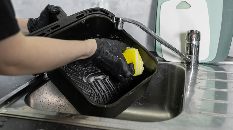 A person scrubbing an air fryer basket