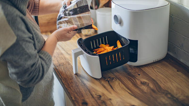 A person cooking potato wedges in air fryer
