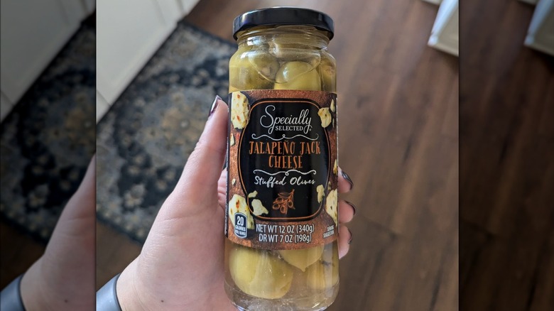 Someone holds a jar of Aldi olives