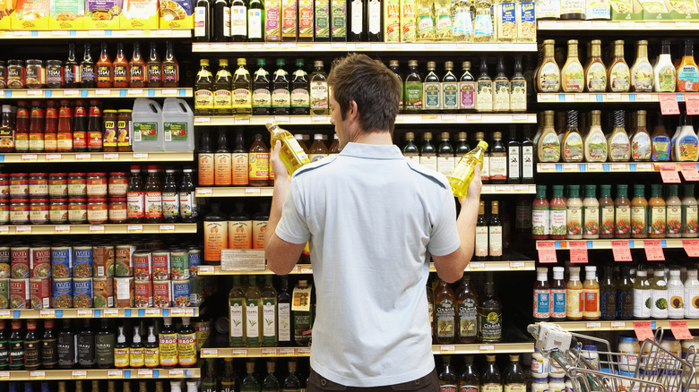 Man deciding between two items in grocery aisle