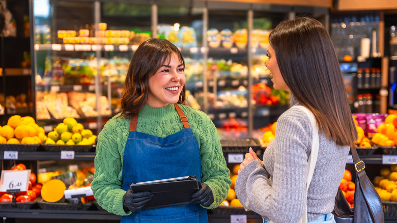 Supermarket employee talking to customer
