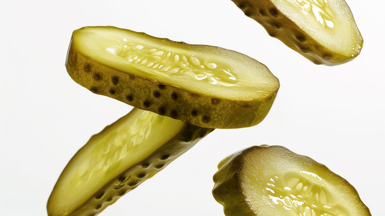 Pickle slices fall on a white background