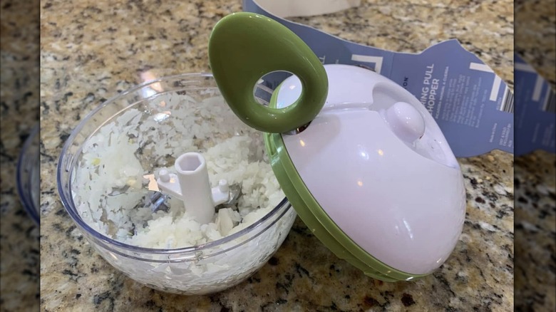 The lid of an Aldi manual chopper sits just off the bowl