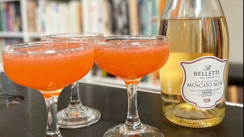 A bottle of Belletti Moscota Rose sits next to three blended drinks