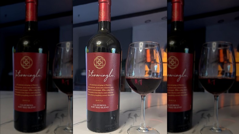 A bottle of Intermingle red wine sits next to a wine glass