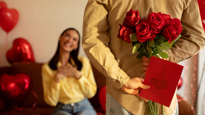 Man holding roses and a card behind his back