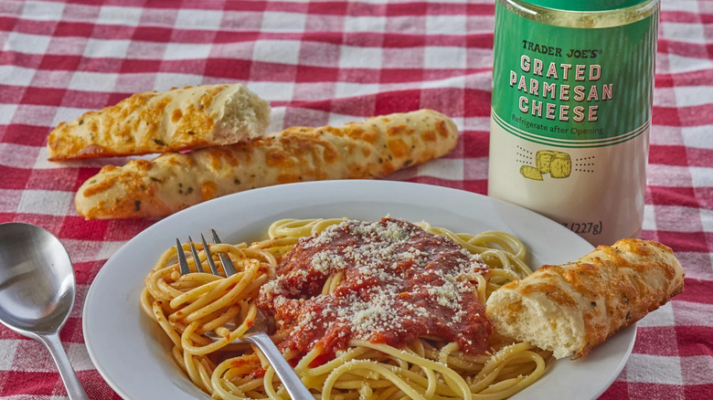 Grated parmesan sold at Trader Joe's on top of spaghetti.