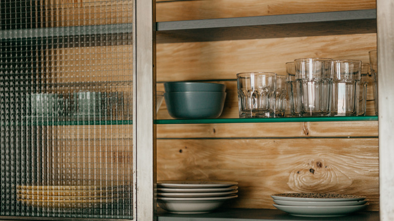 Plates, bowls, and glasses in an glass cabinet with wood backing