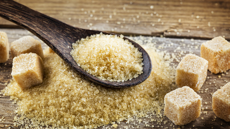 closeup of brown sugar in wooden spoon and sugar cubes