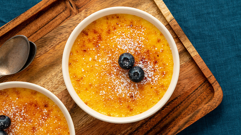 two creme brulee servings on wooden tray