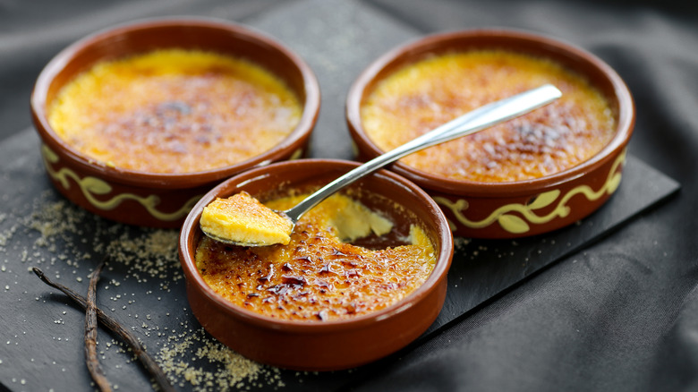 three servings of creme brulee on black table