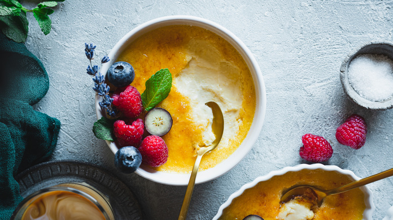 servings of creme brulee with garnishes on blue surface