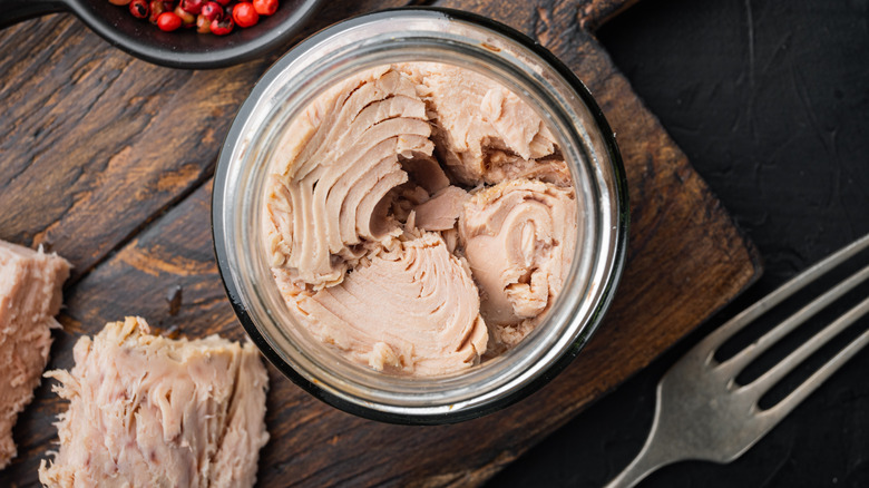 open jar of tuna on a wooden cutting board