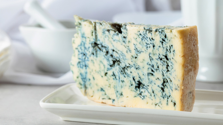 A wedge of Gorgonzola cheese with blue-green veins