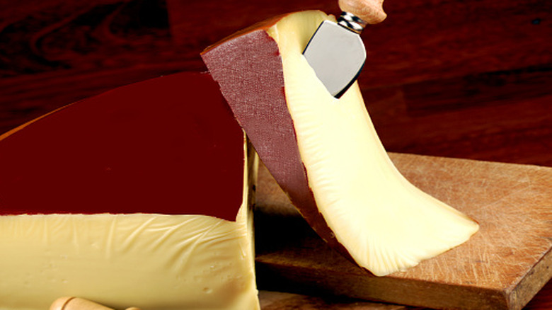 A large wedge of Fontina and a smaller wedge with a small cheese knife stuck in it