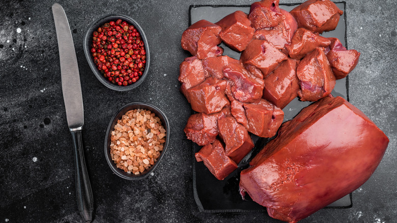 Whole and diced veal liver alongside pink pepper and salt.