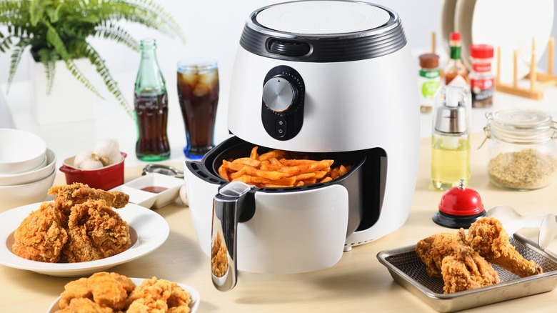 Air fryer next to plates of fried foods