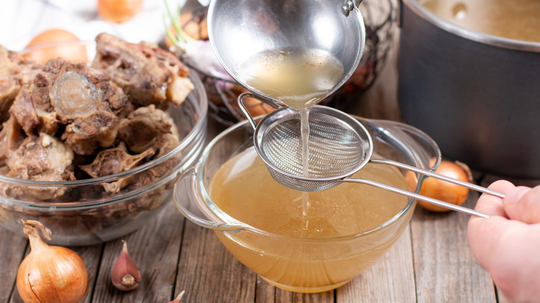 Beef broth being passed through sieve