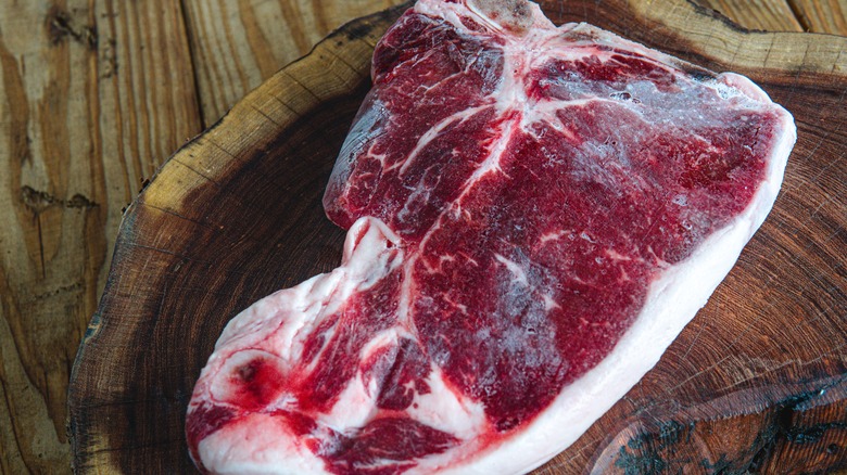 frozen steak on wooden board