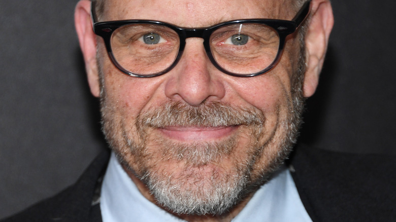 Alton Brown holding up his candy-like bacon strip