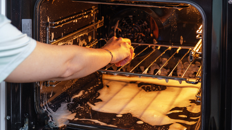 Person cleaning a dirty oven