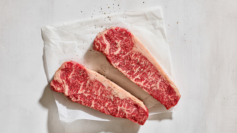 Two Australian wagyu beef steaks on white butcher paper with freshly cracker pepper