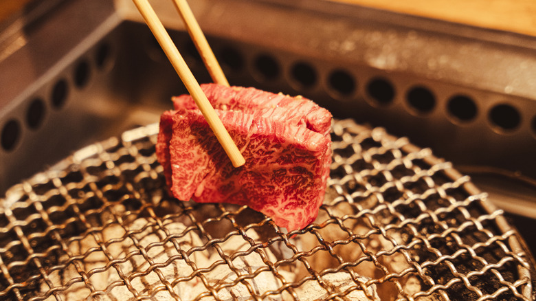 Two pieces of Japanese wagyu held over grill