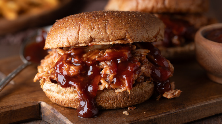 A pulled chicken sandwich oozes barbecue sauce
