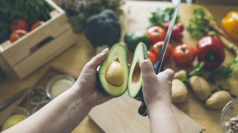 Person slicing open avocado