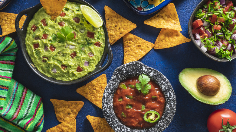 Guacamole and salsa bowls next to tortilla chips