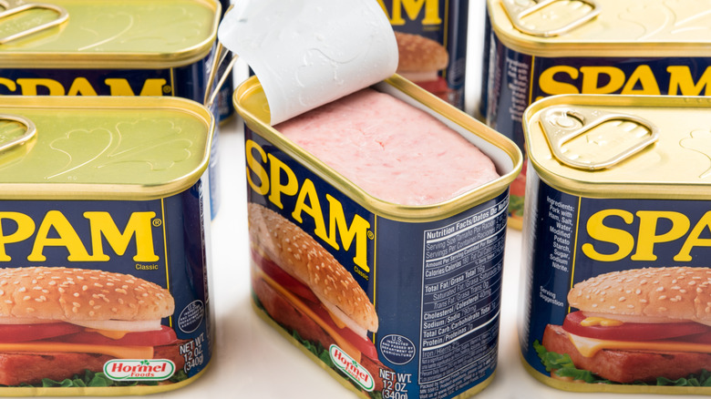 Cans of Spam sit on a white surface.
