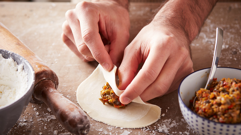 a person filling a dumpling wrapper