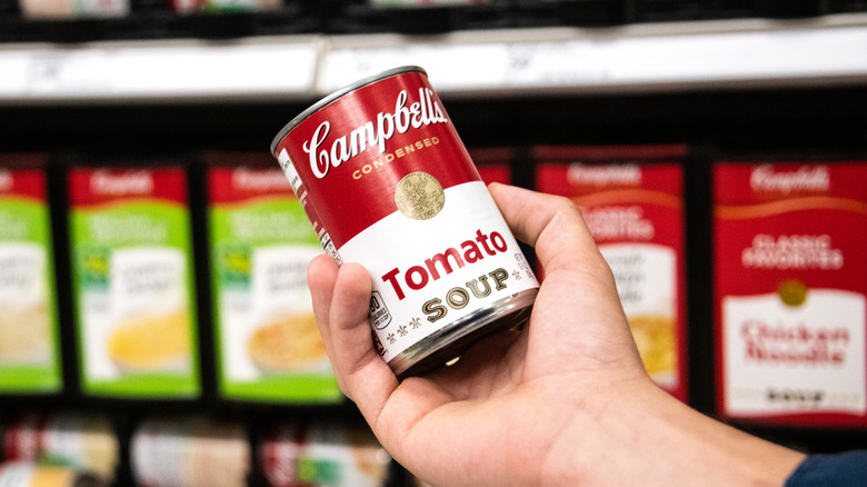 Hand holding Campbell's tomato soup at store