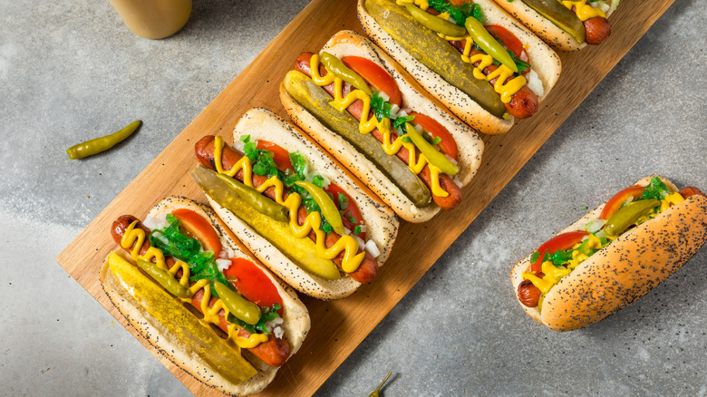 Chicago-style hot dogs on a wooden board.