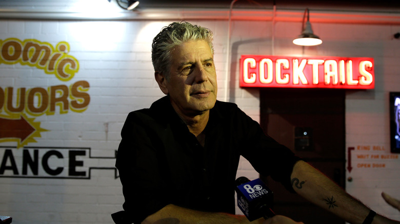 Anthony Bourdain with neon 'cocktails' sign behind