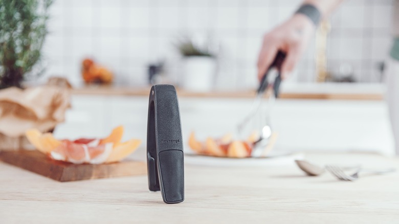 Empty anytongs sit in the foreground as someone uses a pair with forks in to turn food