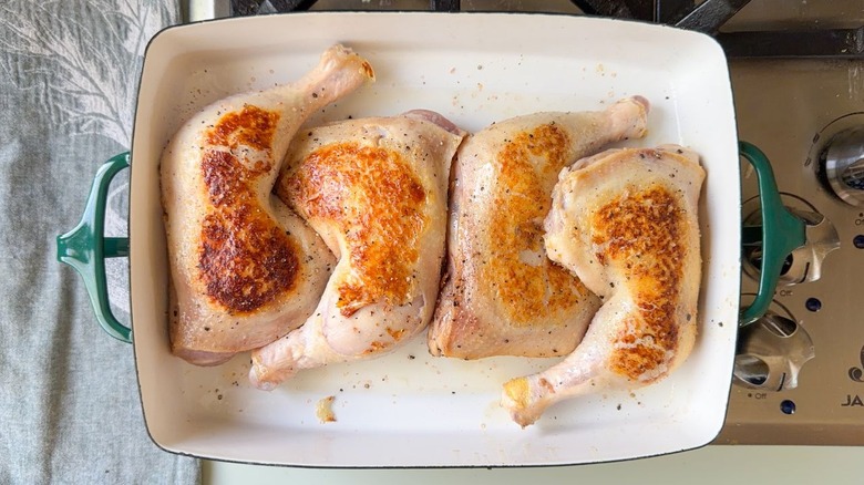 Browned chicken leg quarters in oiled baking dish