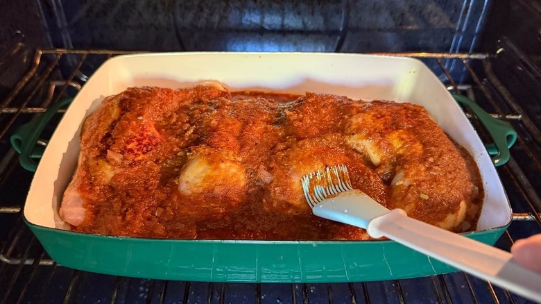 Basting applesauce barbecue chicken in oven with pastry brush