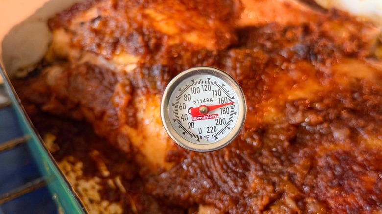 Instant-read thermometer at 165 F inserted into chicken leg quarter