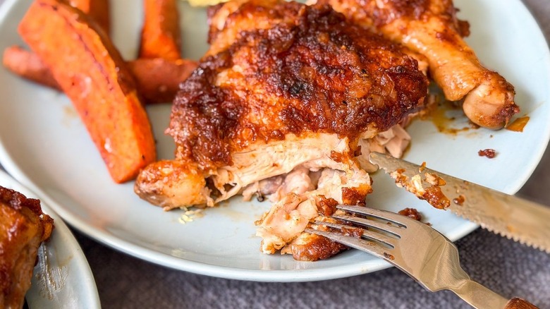 Sliced applesauce barbecue chicken on plate with sweet potato wedges