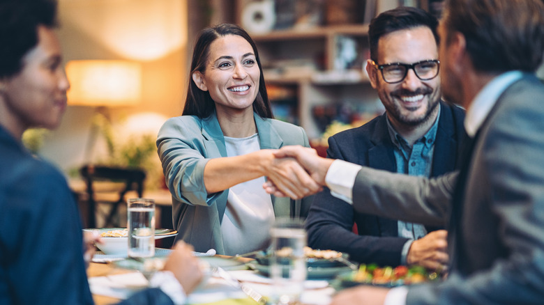 man shaking woman's hand at table 