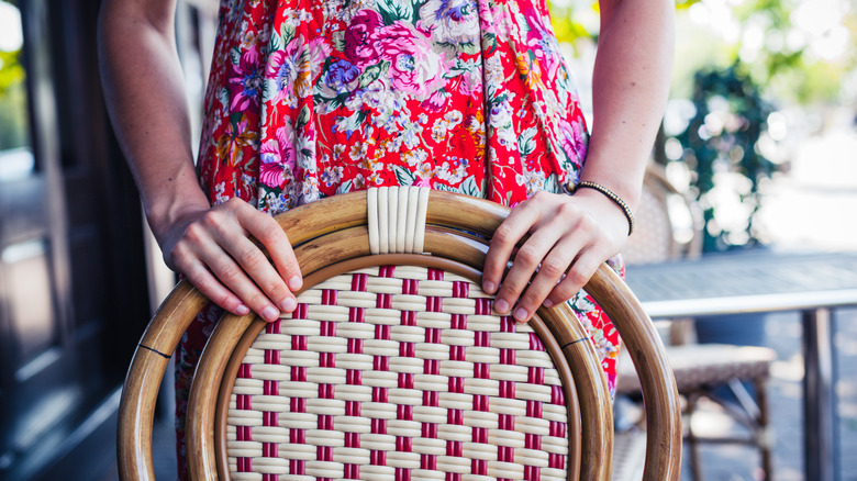 woman standing behind restaurant chair 