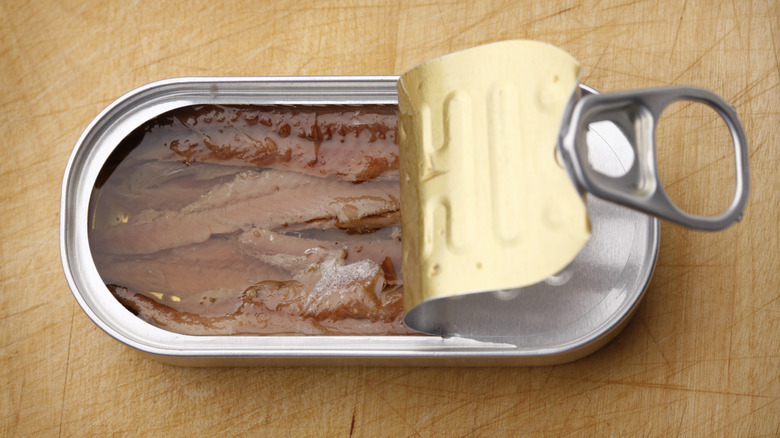 An open can of anchovies in oil